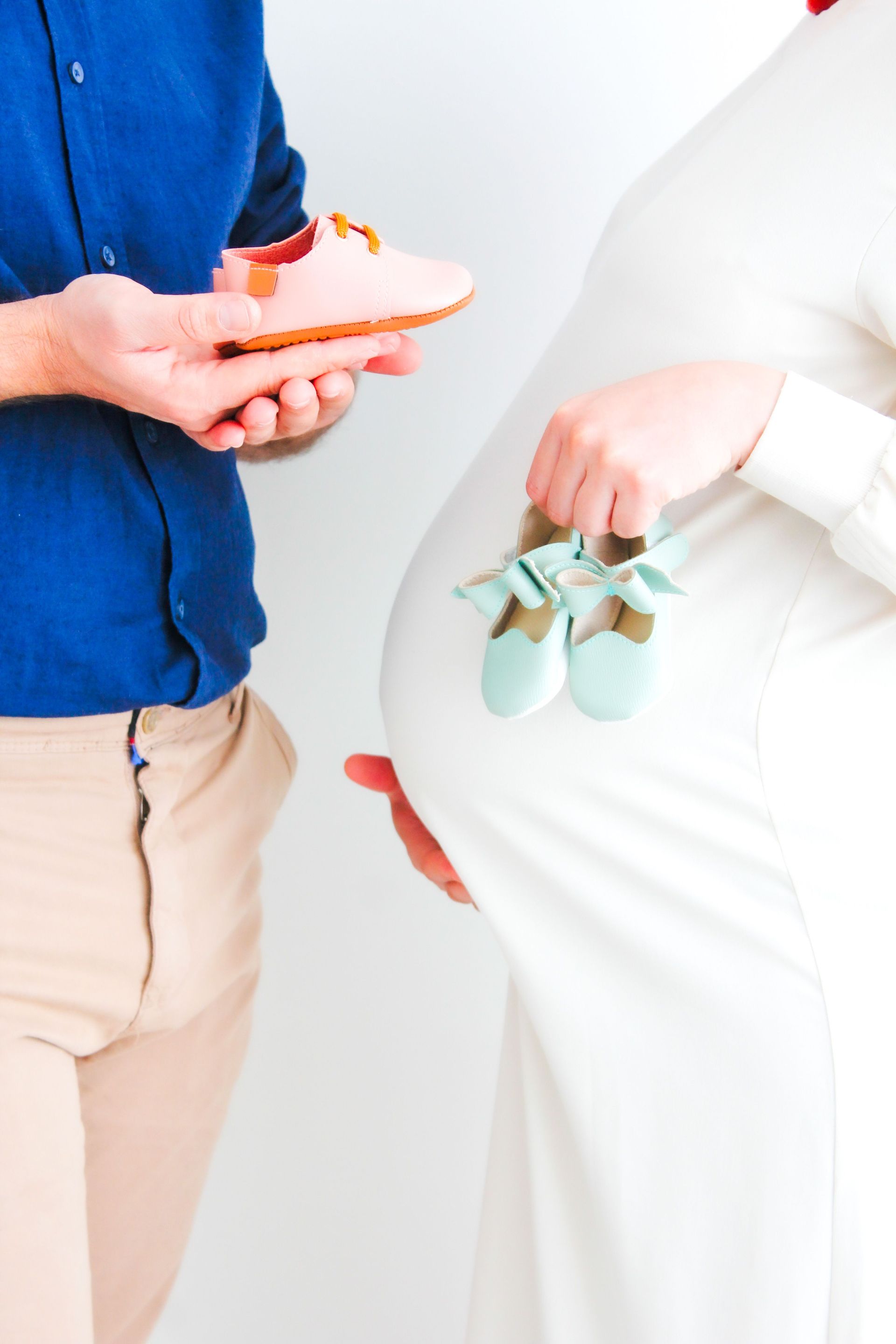 Closeup of expecting parents with baby shoes symbolizing new beginnings and family.